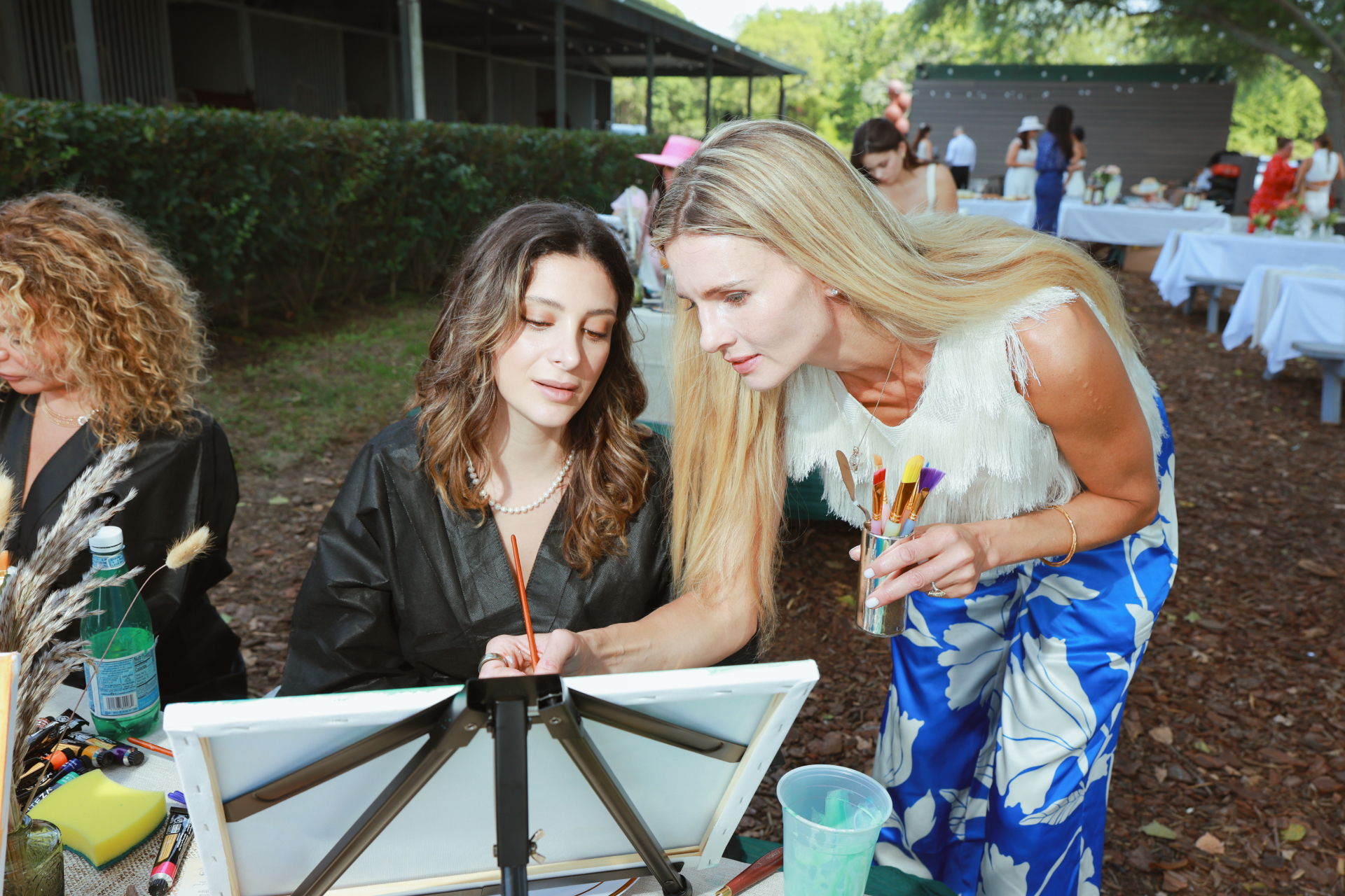Guest guiding another attendee during an ELARTĒ painting session